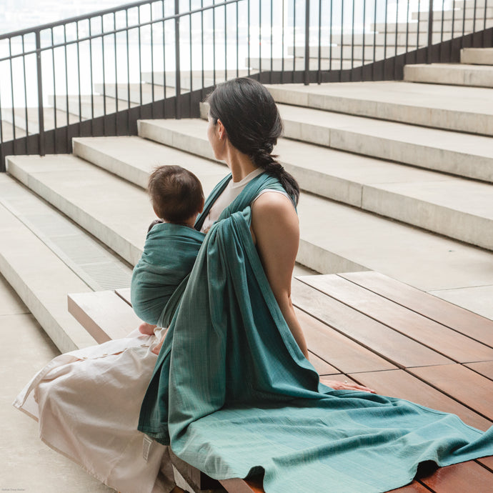 Asian mum babywearing her baby in teal colour wrap